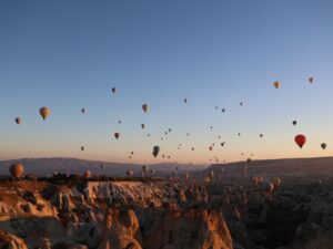Dozens of hot air balloons rising at sunrise over the valleys of Cappadocia