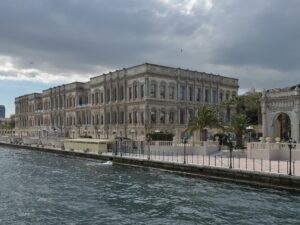 Weather in Istanbul on a changeable day: the Çırağan Palace and its gate beside the Bosphorus under heavy gray clouds with a gap of blue sky