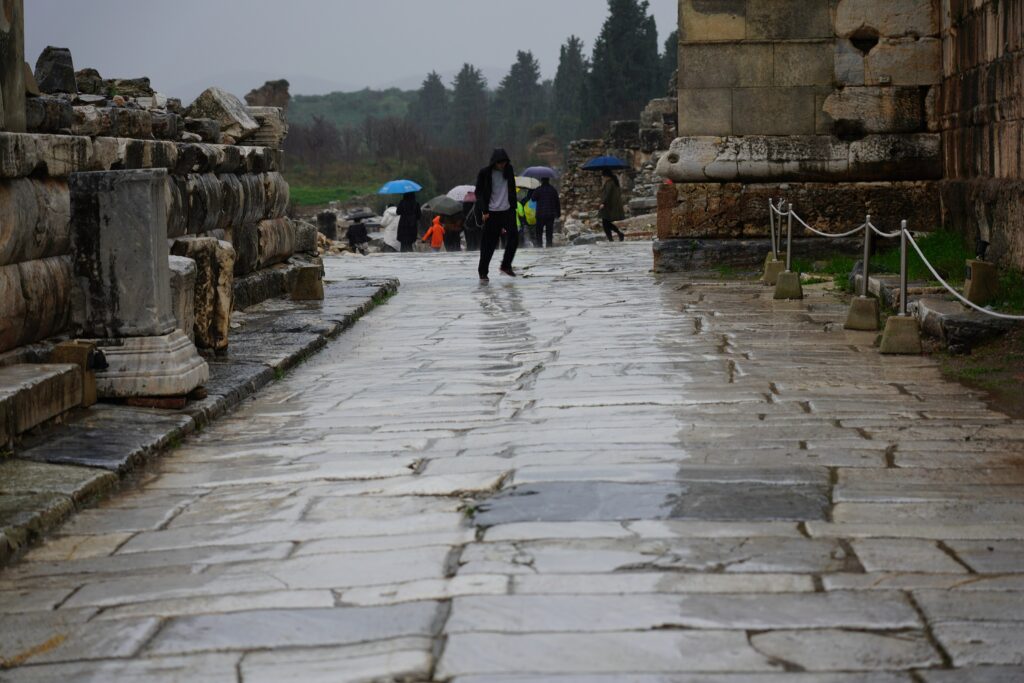 A Tour Under the Rain in Ephesus 2 Rain in Ephesus makes the worn marble street shiny and slippery, with visitors under umbrellas in the distance