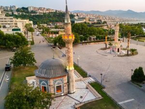Aerial view of the city center of Izmir at Konak Square, with the tiled Konak Mosque in front, the Clock Tower on the right and the bay and hills behind